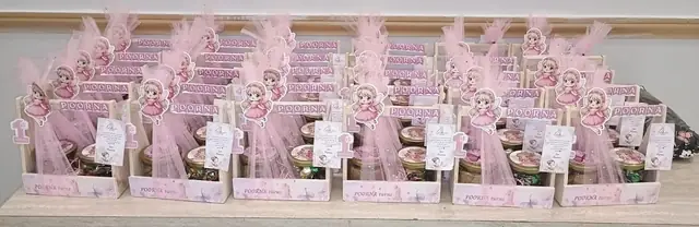 Rows of pink wooden crates, each with a fairy cut-out name topper, a jar of wrapped chocolates and a printed tag, finished with pink tulle.
